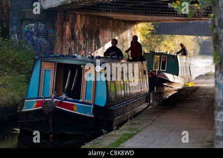 Boote fahren unter einer Eisenbahnbrücke auf dem Birmingham & Worcester-Kanal im Selly Oak, Birmingham, UK. Stockfoto