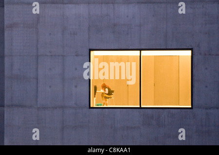 Graue Betonblöcke und großes Fenster der Hepworth Gallery (Beleuchtung innen und Frau am Tisch sitzend) - Wakefield, West Yorkshire, England, Großbritannien. Stockfoto