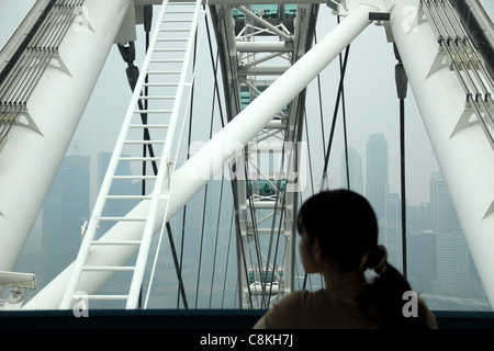 Junge Mädchen schaut aus Glas Beförderung von Singapore Flyer, wie es oben, bevor es hinunter und aufschlussreichen Blick auf die Stadt erreicht. Stockfoto