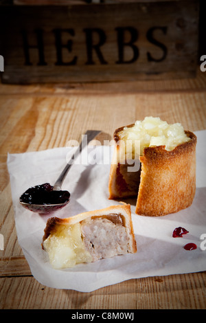 traditionelle Pork Pie, garniert mit Apfel-Sauce auf Schneidbrett aus Holz. Stockfoto