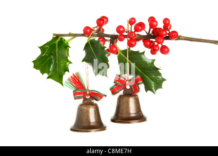 Weihnachtsbaum Dekoration Messing Glocken hängen von einem Holly-Zweig mit roten reifen Beeren isoliert gegen weiß Stockfoto