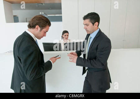 Hispanische Geschäftsleute halten Handys im Büro Stockfoto
