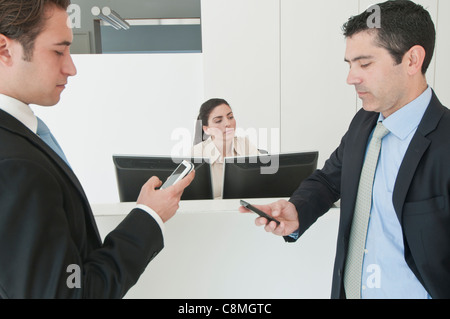 Hispanische Geschäftsleute halten Handys im Büro Stockfoto