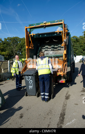 Abzulehnen Sie Arbeiter von Basildon Rat in Essex auf Rückseite des Staubwagen laden und Entleerung wheely (mit Rädern) Lagerplätze in hinten arbeiten. Stockfoto