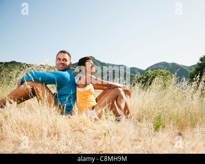 Paar sitzen Rücken an Rücken im Bereich nach dem Training Stockfoto