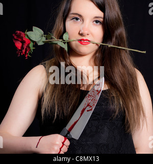 junge Frau mit einem blutigen Messer und eine rote rose Stockfoto