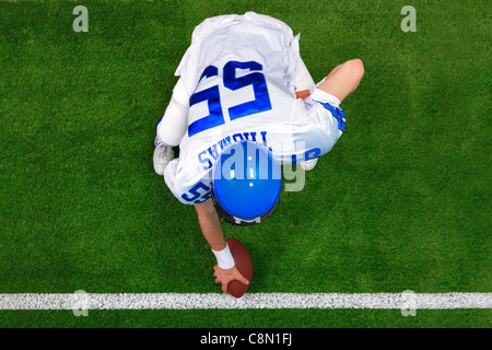 Obenliegende Foto einer American-Football-Spieler Zentrum Straftat rund um den Ball zu fangen. Stockfoto