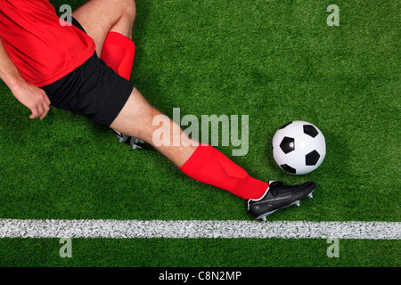 Obenliegende Foto eines Fußball- oder Fußball-Spieler rutschen in den Ball über die Seitenlinie speichern Stockfoto