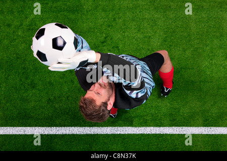 Obenliegende Foto von einem Fußball-Torwart springen in der Luft den Ball auf der Linie retten. Schwerpunkt ist auf seinem Gesicht. Stockfoto