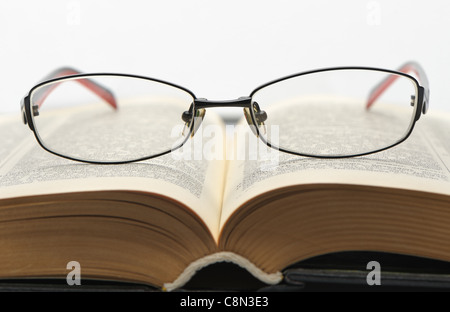 Brille auf dem alten dicken Buch. Isoliert auf weißem Hintergrund Stockfoto