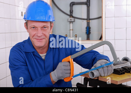 Klempner Sägen Länge des Kunststoff-Rohr Stockfoto