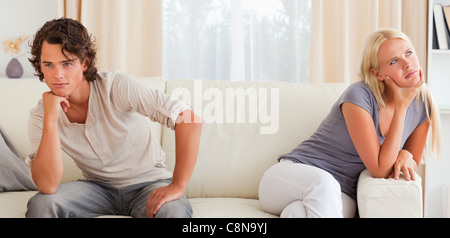 Junges Paar auf einer Couch sitzend verärgert Stockfoto