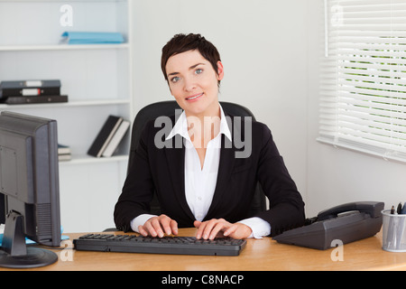 Junge Sekretärin auf ihrer Tastatur tippen Stockfoto