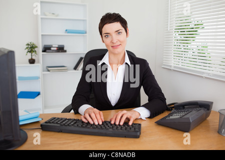 Lächelnde Sekretärin auf ihrer Tastatur tippen Stockfoto