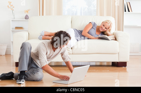 Mann mit einem Laptop, während seine Freundin ein Buch hält Stockfoto