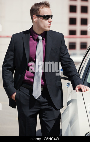 Gut aussehend zuversichtlich Geschäftsmann sein Auto gelehnt. Stockfoto