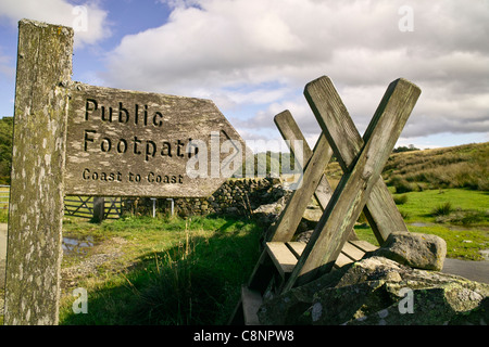 Nahaufnahme eines hölzernen Fußweg-Zeichen neben hölzernen Stil über eine Trockensteinmauer in Cumbria auf dem Fußweg von Küste zu Küste Stockfoto