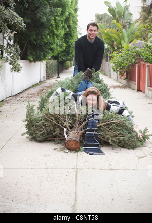 Kaukasische paar ziehen Weihnachtsbaum in der Gasse Stockfoto