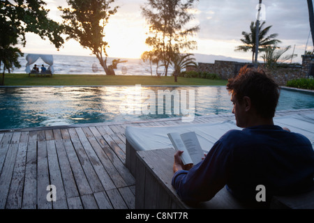 Kaukasischen Mann lesen am Pool Stockfoto