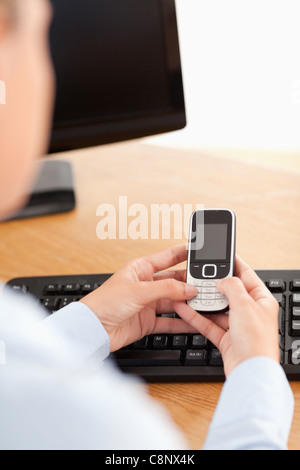 Eine Geschäftsfrau halten eines Handys am Arbeitsplatz Stockfoto