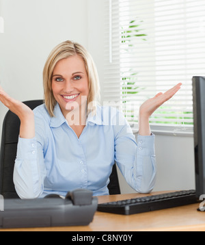 Lächelnde Frau sitzt hinter dem Schreibtisch nicht mit einer Ahnung, was als nächstes zu tun Stockfoto