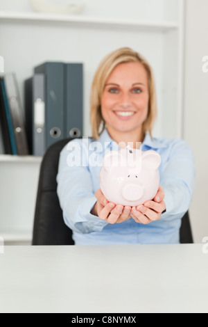 Wunderschöne Geschäftsfrau hält ein Sparschwein Stockfoto
