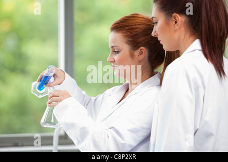 Junge Wissenschaftler, die Flüssigkeit in einen Erlenmeyerkolben gießen Stockfoto