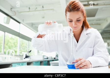 Rothaarige fokussierte Wissenschaftler Flüssigkeit in eine Flasche gießen Stockfoto