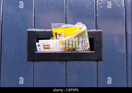 Briefe und e-Mails ragte aus einer Uk-Briefkasten in der Tür eines Hauses Stockfoto