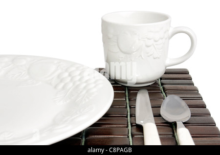 Speiseteller, strukturierte weiße China mit Trauben und Tomaten Design über einem dunklen Holz Tischset. Stockfoto