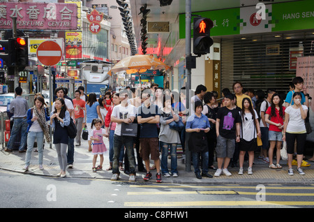 Eine Gruppe von Menschen an einem Fußgängerüberweg, warten auf die grüne Mann in Hong Kong Stockfoto