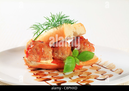 Stangenbrot mit Frikadellen gefüllt und garniert mit roter sauce Stockfoto