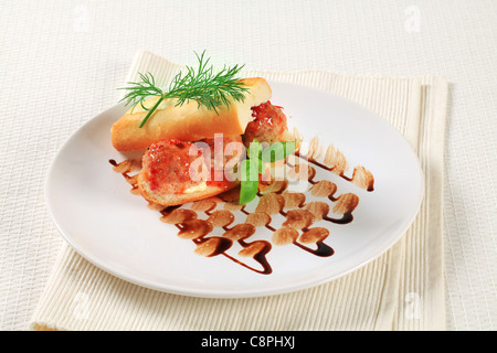 Stangenbrot mit Frikadellen gefüllt und garniert mit roter sauce Stockfoto