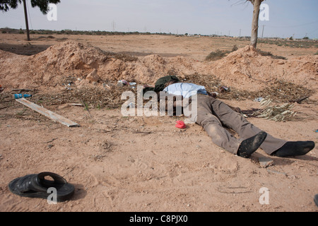 Einer der Oberst Gaddafis bewacht legt Toten in den Straßen auf Sirt nach einem NATO-Luftangriff auf Gaddafi-Konvoi. Stockfoto