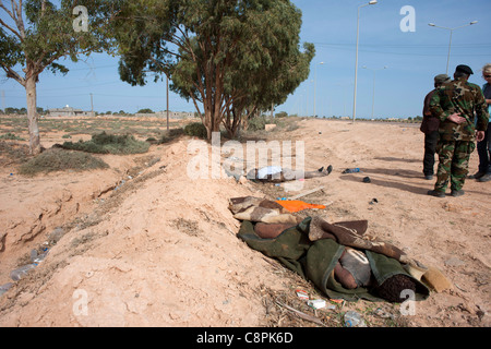 Einer der Oberst Gaddafis bewacht legt Toten in den Straßen auf Sirt nach einem NATO-Luftangriff auf Gaddafi-Konvoi. Stockfoto