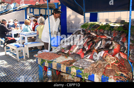 Touristen Essen im Außenbereich durch die Frischfisch-Grills auf der Promenade in der Nähe des Hafens in Essaouira; Marokko. Stockfoto