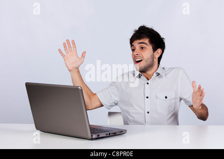 junger Mann überrascht und zufrieden mit etwas, das er auf seinem Laptop sehen Stockfoto