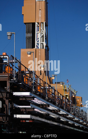 Alaska North Slope. Drilling Rig Derrick aufgereiht mit einer Reihe von Bohrlochköpfe im Vordergrund Stockfoto