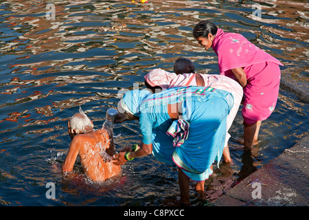 Frauen waschen einen älteren Verwandten (ein hindu-Tradition). RAM "Kund". Godavari Fluß. Nashik. Indien Stockfoto