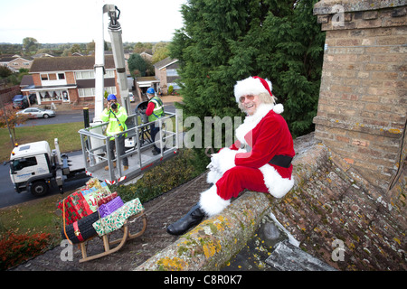 Santa Claus liefert seine Dach Top Magie mit Hilfe einer Hubarbeitsbühne UK Stockfoto