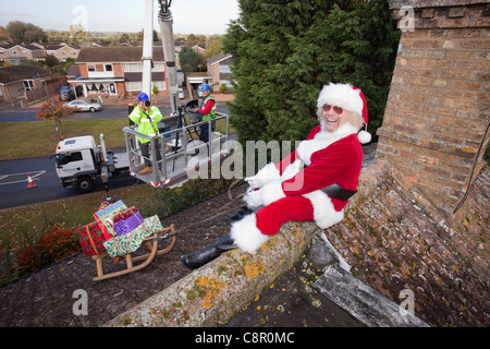 Santa Claus liefert seine Dach Top Magie mit Hilfe einer Hubarbeitsbühne UK Stockfoto