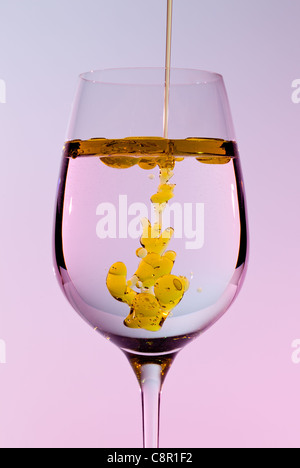 Olivenöl in einer großen Weinkelch goldene Perlen in der Flüssigkeit bilden Stockfoto