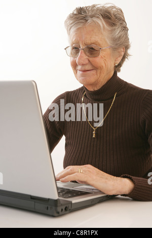 Eine glückliche alte Dame mit einem Laptop. Stockfoto