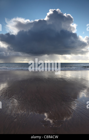 Gewitterwolken und schweren Bands von Regen über dem Meer spiegelt sich auf einem Strand Vereinigtes Königreich UK Stockfoto