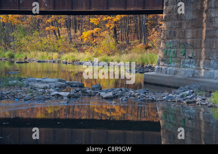 Reflexionen des Herbstes unter der Eisenbahnbrücke Ile Perrot. Stockfoto