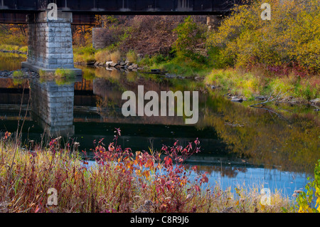 Reflexionen des Herbstes unter der Eisenbahnbrücke Ile Perrot. Stockfoto