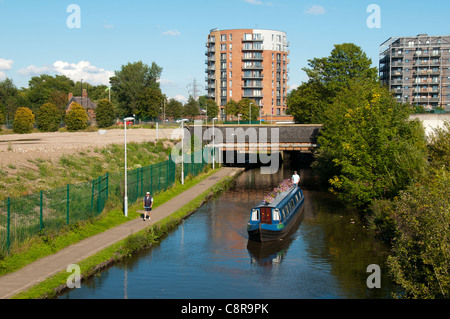 Ein Schmalboot auf dem Ashton Canal, Clayton, Eastlands, Manchester, England, Großbritannien. Der Drum Appartementblock dahinter. Stockfoto