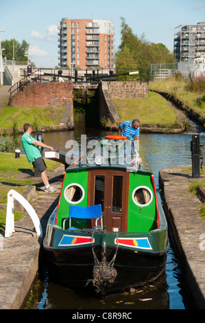 Ein Schmalboot in einer Schleuse auf dem Ashton Canal, Clayton, Eastlands, Manchester, England, Großbritannien. Der Drum Appartementblock dahinter. Stockfoto