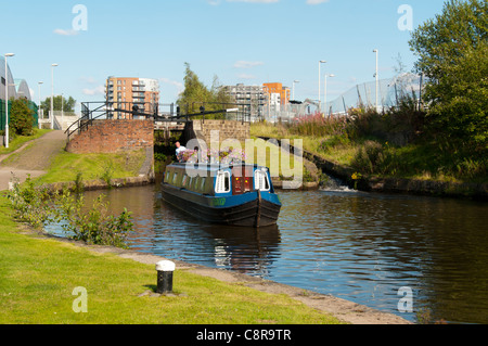 Ein schmales Boot, das aus einer Schleuse auf dem Ashton Canal, Clayton, Eastlands, Manchester, England, UK herausfährt. Stockfoto