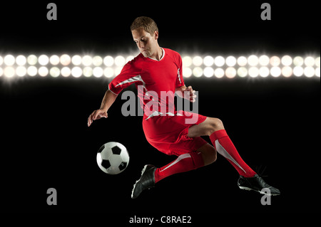 Fußball-Spieler springen in der Luft treten Kugel in der Nacht Stockfoto